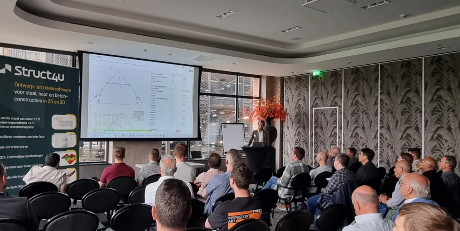 Presentation to a seated audience, with a parametric roof truss on the screen and a Struct4U banner on the left